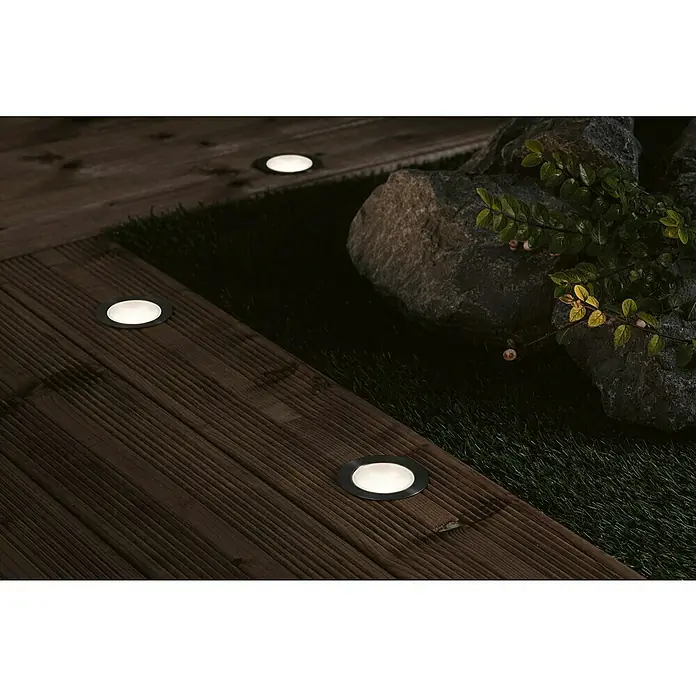 Paulmann Plug & Shine Bodeneinbauleuchten-Basis-Set Floor - Ø x H: 7 x 3 cm, 3 Stk., RGBW - Bodeneinbauleuchten auf einer Holzterrasse mit Steinen und Pflanzen.