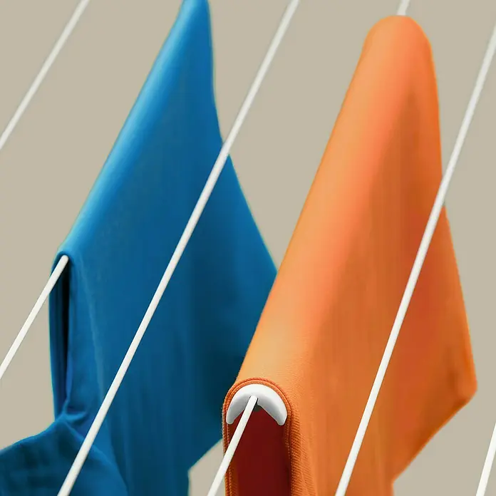 Juwel Wäsche-Faltenstop - 4 -tlg., Kunststoff - Nahaufnahme von blauen und orangefarbenen Stoffen, die auf einer weißen Wäscheleine zum Trocknen aufgehängt sind.