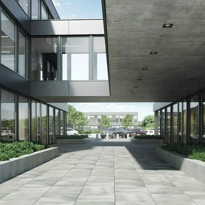 Cersanit Terrassenfliese Beton Grey Light - 59,3 x 59,3 x 2 cm, Grau, Matt - Außenaufnahme eines Gebäudes mit einem Pflasterweg, der die Architektur betont. Die Pflastersteine verleihen dem Außenbereich Struktur und Eleganz.