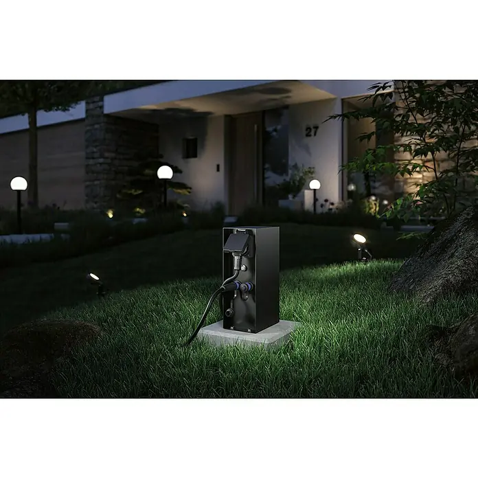 Paulmann Plug & Shine Steckdosensäule Rio - Anthrazit, Höhe: 23 cm, IP44, Mit Dämmerungssensor - Diese Aufnahme zeigt eine moderne Stromtankstelle für Elektroautos in einem gepflegten Garten vor einem stilvollen Haus.