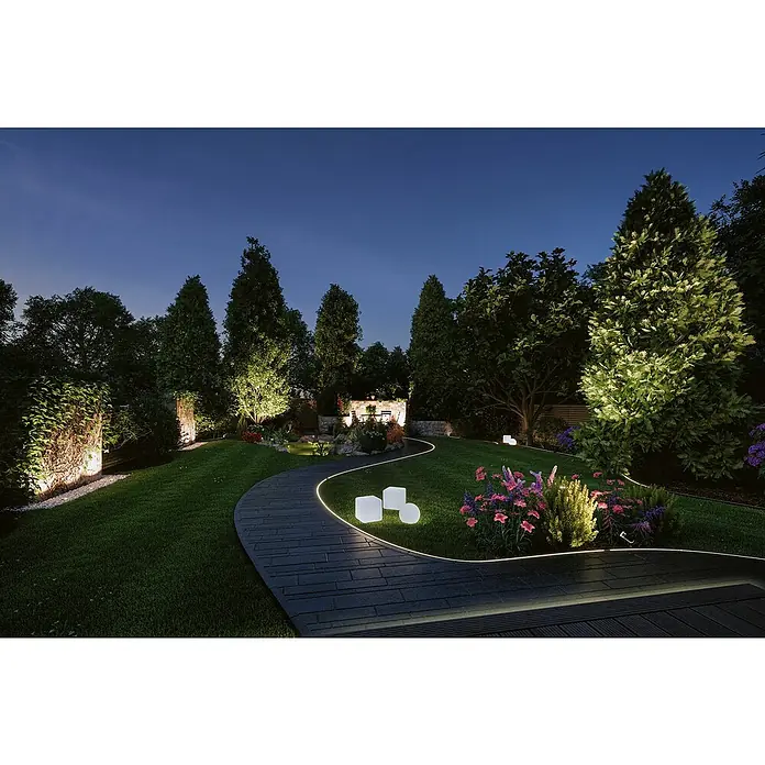 Paulmann Plug & Shine LED-Band Smooth Strip - Länge: 5 m, RGBW, 700 lm, 24 V - Eine dunkle, bezaubernde Gartenlandschaft mit einem beleuchteten Weg, der sich durch das üppige Grün schlängelt und eine märchenhafte Atmosphäre schafft.