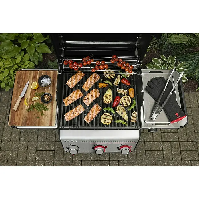 Weber Gasgrill Spirit E-310 - Grillfläche (B x T): 52 x 44 cm, 7 kW, Anzahl Brenner: 3 Stk. - Ein Weber Spirit Gasgrill mit köstlichem Grillgut wie Lachs, Gemüse und Tomaten, bereit für ein Festmahl im Freien.