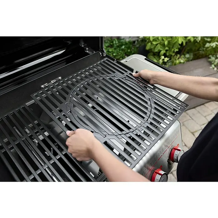 Weber Gasgrill Spirit E-335 GBS - Grillfläche (B x T): 52 x 44 cm, 9,1 kW, Anzahl Brenner: 3 Stk. - Nahaufnahme eines Grills mit einer Person, die einen runden Grillrost einsetzt, um das Grillen zu erleichtern und die Speisen optimal zuzubereiten.