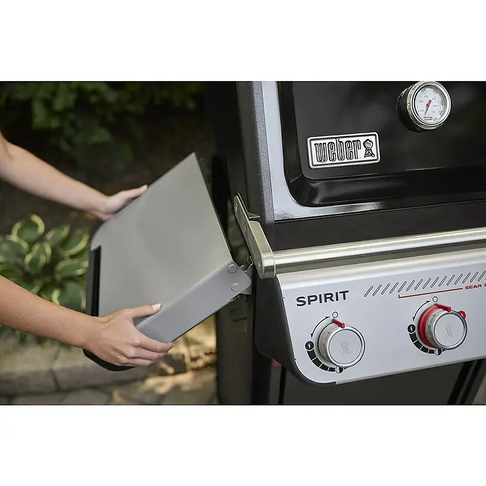 Weber Gasgrill Spirit E-325 GBS - Grillfläche (B x T): 52 x 44 cm, 9,1 kW, Anzahl Brenner: 3 Stk. - Nahaufnahme des Weber Spirit Sear 2-Gasgrills mit heruntergeklappter Seitenablage, der die Bedienelemente und das Temperaturmessgerät zeigt.