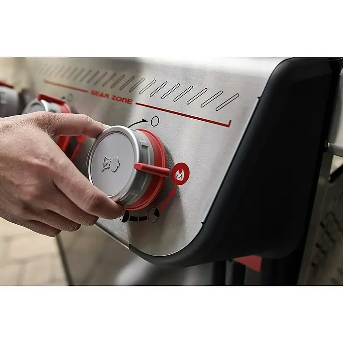 Weber Gasgrill Spirit E-335 GBS - Grillfläche (B x T): 52 x 44 cm, 9,1 kW, Anzahl Brenner: 3 Stk. - Nahaufnahme eines Gasgrills mit einem roten Knopf, der von einer Hand gedreht wird, um die Hitze zu regulieren.