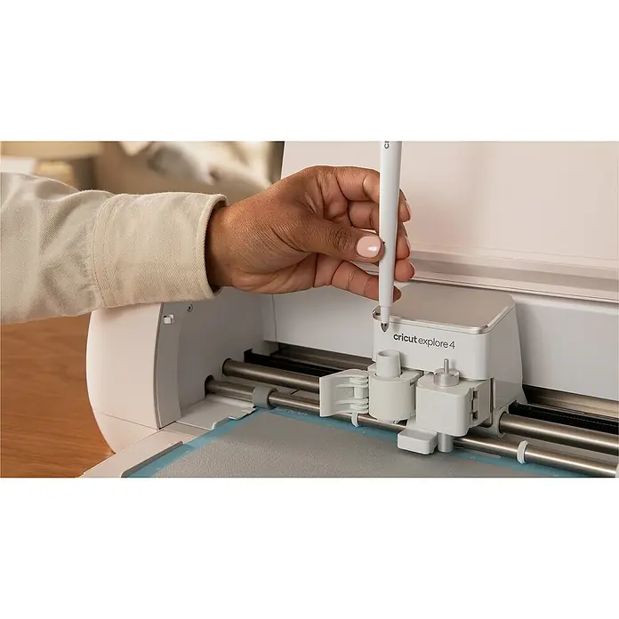 Cricut Plotter de corte Explore 4 - Blanco, Bluetooth, Ancho de corte: 29,7 cm, Longitud de corte: 3,6 m - Un primer plano de una máquina de corte Cricut Explore 4 con una persona insertando un bolígrafo en la máquina.