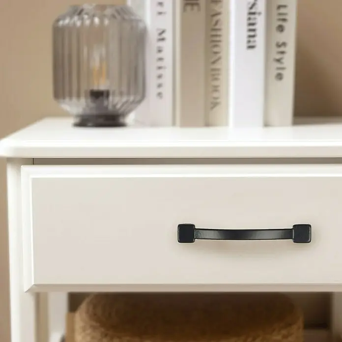 Rei Möbelgriff - Lochabstand: 64 mm, Sonstige, Schwarz, L x B x H: 72 x 10 x 17 mm - Weißer Nachttisch mit schwarzem Schubladengriff, darauf eine Lampe und Bücher.