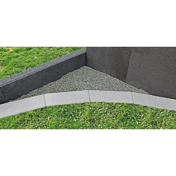 Christoph Mähstein Trapez - 24 x 10 x 4,2 cm, Silbergrau, Beton - Nahaufnahme einer Gartenecke mit grauen Steinen, dunklen Bordsteinen und Rasen, die die klaren Linien und die Materialkombination hervorhebt.