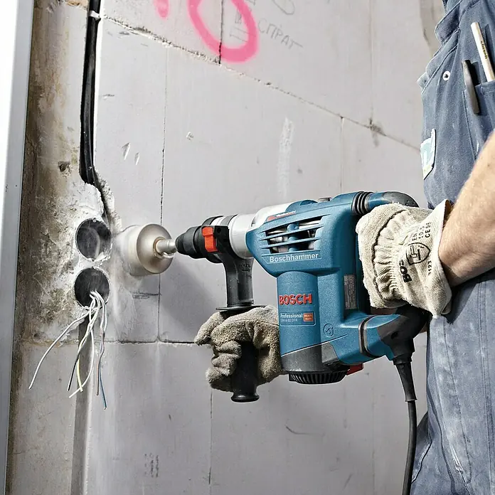 Bosch Professional Kombihammer GBH 4-32 DFR - 900 W, 4,2 J, SDS-Plus-Aufnahme - Der Boschhammer in Aktion: Ein Handwerker bohrt mit dem Boschhammer ein Loch in eine Wand, ideal für Bauprojekte.