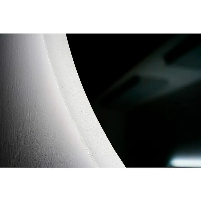 LedImex Espejo con luz Bélgica - Diámetro: 50 cm - Primer plano de un elemento arquitectónico curvo y blanco con una textura ligera sobre un fondo oscuro, destacando su forma y material.