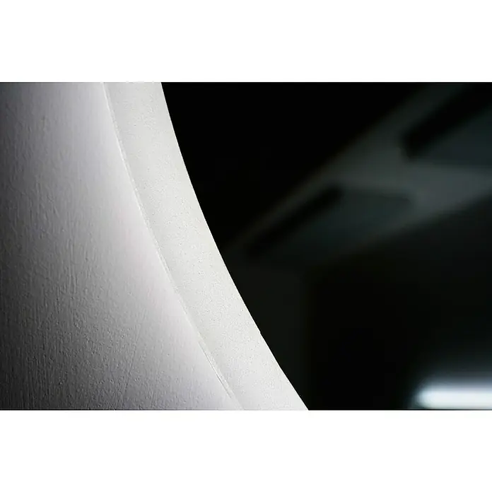LedImex Espejo con luz Londres - Diámetro: 70 cm, Sensor, Función antivaho - Primer plano de una pared blanca curva con una superficie sutilmente texturizada, que transiciona a un fondo oscuro.