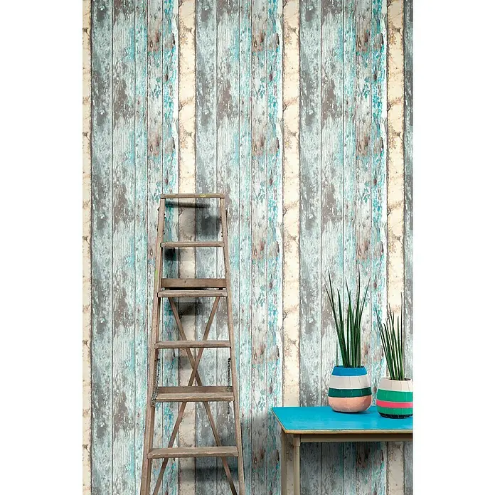 Papel pintado Tablilla madera - Multicolor, Efecto madera, 10,05 x 0,53 m - Foto de una escalera y dos plantas sobre una mesa, frente a una pared de madera con pintura azul.
