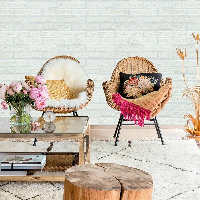 Papel pintado Ladrillo blanco - Beige/Crema/Blanco, Efecto piedra, 10 x 0,53 m - Elegante interior con sillones de mimbre, una mesa de centro dorada y una elegante mesa auxiliar de tocón de árbol sobre una alfombra marroquí.
