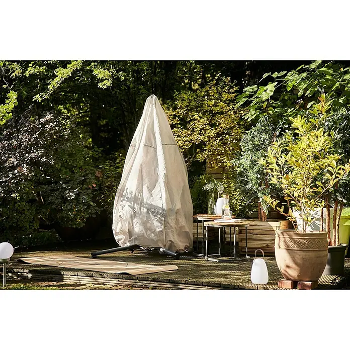 Siena Garden Hängesessel Yobaya mit Schutzhülle - L x B x H: 106 x 123 x 195 cm, Blau - Eine Gartenszene mit einem abgedeckten Gartenmöbelstück, Beistelltischen und Pflanzen in Töpfen, die eine ruhige und gepflegte Außenanlage zeigen.