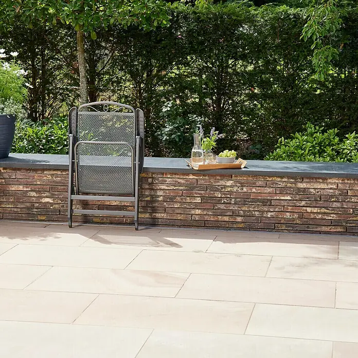 Siena Garden Klappstuhl Set Elda - 4 Stk., Klappbar, Anthrazit, B x T x H: 46 x 60 x 103 cm - Ein grauer Klappstuhl aus Metall steht zusammengeklappt auf einer Terrasse. Auf einer Mauer stehen Getränke und Obst bereit für eine entspannte Pause.
