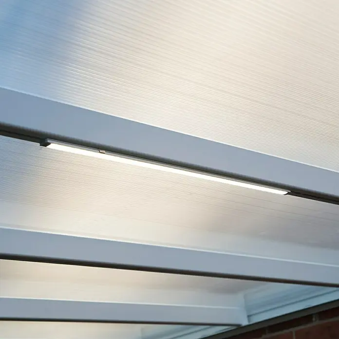Palram – Canopia Lámpara fluorescente LED - 10 W, 1,8 x 67 x 0,7 cm - Primer plano de una lámpara LED montada debajo de un panel de techo blanco translúcido, que emite una luz brillante y difusa.