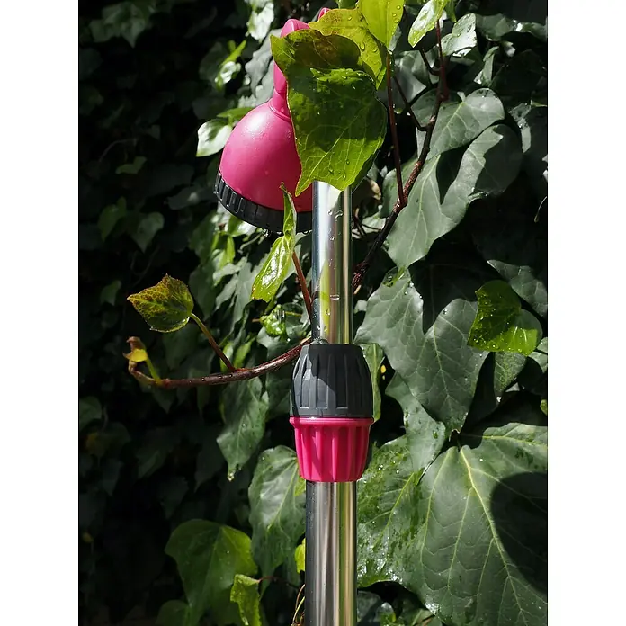 Ducha de jardín con trípode - Altura: 240 cm, Trípode, Aluminio, Fucsia - Primer plano de un aspersor de jardín rosa con un poste plateado, rodeado de exuberante vegetación. Perfecto para regar tu jardín.