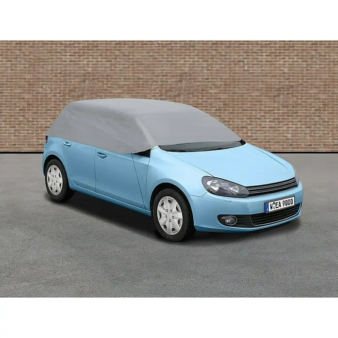 APA Auto-Halbgarage - Größe: M - Ein hellblaues Auto mit einer grauen Autoabdeckung vor einer Ziegelmauer. Die Autoabdeckung schützt das Fahrzeug vor Witterungseinflüssen.