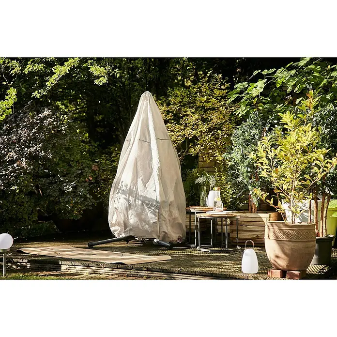 Siena Garden Hängesessel Yobaya mit Schutzhülle - L x B x H: 106 x 123 x 195 cm, Grau - Ein Garten mit einer abgedeckten Schaukel, umgeben von üppigem Grün, mit Beistelltischen und Blumentöpfen im Freien.