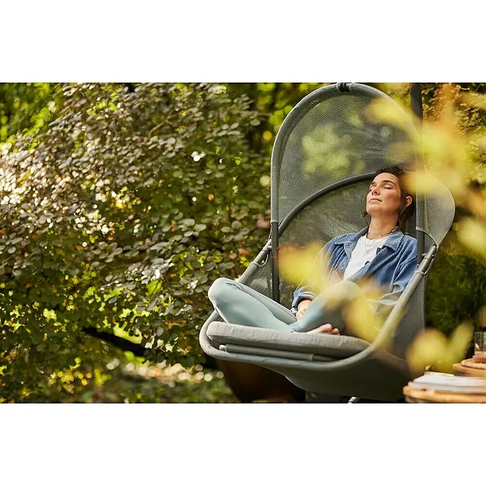 Siena Garden Hängesessel Yobaya mit Schutzhülle - L x B x H: 106 x 123 x 195 cm, Blau - Eine Frau entspannt sich in einem Hängesessel im Freien, umgeben von üppigem Grün. Der Sessel bietet Komfort und Stil für den Garten.