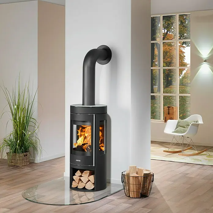 Justus Kaminofen Mino Trios 2.0 - 5,5 kW, Raumheizvermögen: 88 m³, Farbe Verkleidung: Glas, Schwarz - Ein Justus Kaminofen mit Holz in einem modern eingerichteten Raum, der Wärme und Stil vereint.
