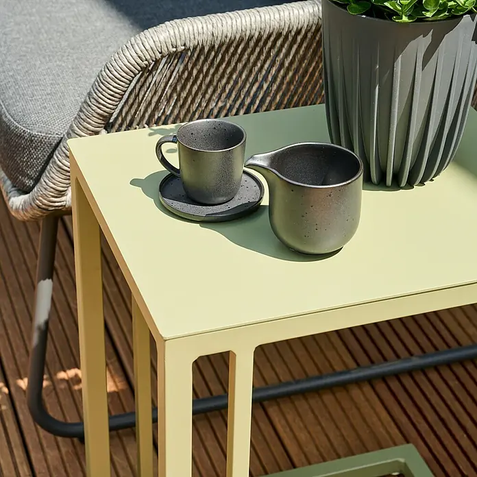 Siena Garden Garten-Beistelltisch Ramo - L x B x H: 33,5 x 40 x 50 cm, Melamin, Quadratisch, Olive - Nahaufnahme eines Tisches mit Keramikgeschirr, darunter eine Tasse, eine Untertasse und ein Milchkännchen.