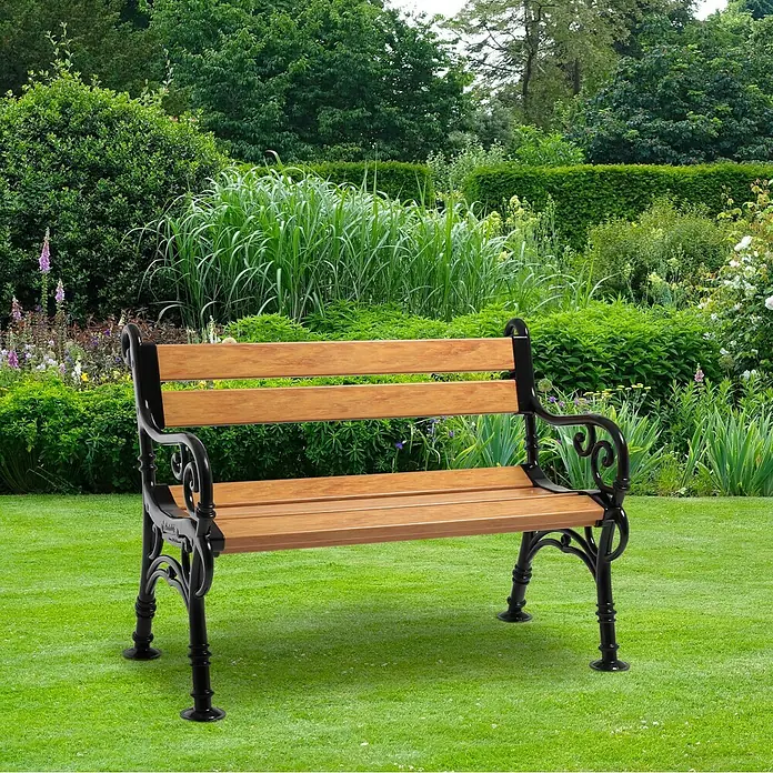 Blome Gartenbank Linderhof - B x T x H: 115 x 60 x 85 cm, Holzoptik - Eine Parkbank mit Holzsitzen und einem schwarzen Metallgestell steht auf einem Rasen vor Büschen.