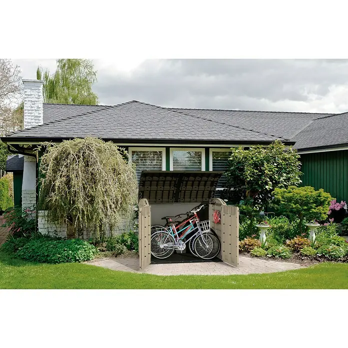 Keter Arcón Store It Out Ultra - L x An x Al: 113 x 177 x 134 cm, Marrón claro - Un cobertizo para bicicletas con dos bicicletas en un jardín frente a una casa.