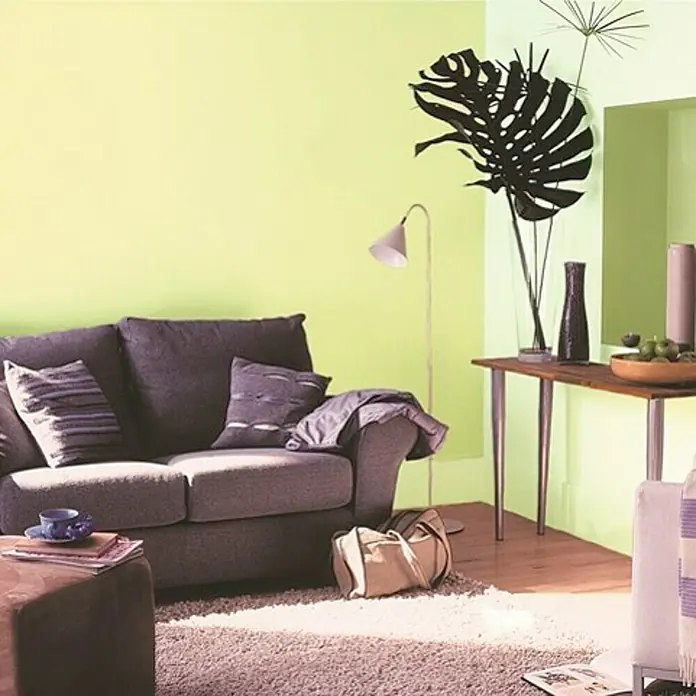 Bruguer Colores del Mundo Pintura para paredes - Amazonas matiz verde, Mate, 4 l - Sala de estar con un sofá gris, una mesa de madera y paredes verdes. La decoración elegante le da al espacio un ambiente acogedor.