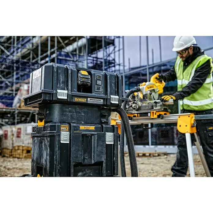 DeWalt Caja para herramientas DWST83346-1 - L x An x Al: 333 x 440 x 302 mm, Plástico, Con cerradura - Sistema de herramientas modular DeWALT negro con extractor de polvo para sierra ingletadora, usado por un trabajador.
