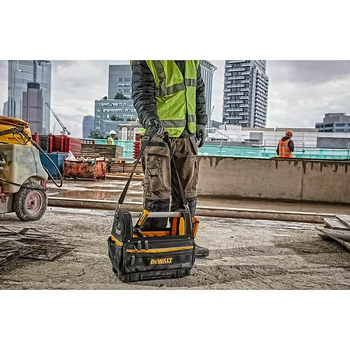 DeWalt T-STAK Bolsa para herramientas - L x An x Al: 25 x 45 x 35 cm, Textil, Capacidad de carga: 30 kg - Un trabajador lleva una bolsa de herramientas DeWalt TSTAK negra y amarilla en una obra.