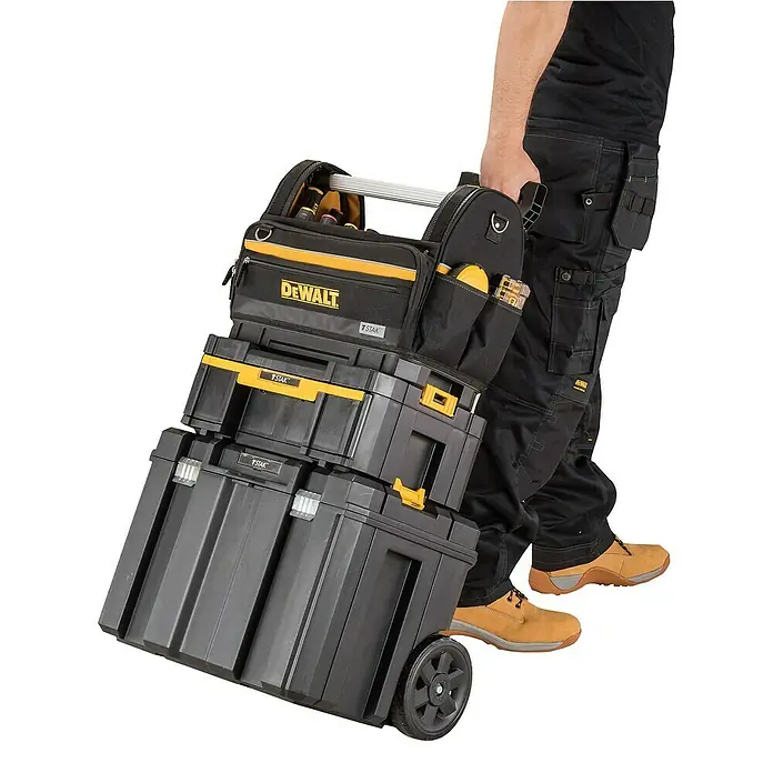 DeWalt T-STAK Bolsa para herramientas - L x An x Al: 25 x 45 x 35 cm, Textil, Capacidad de carga: 30 kg - Persona tirando de un sistema modular de cajas de herramientas DeWalt TSTAK negro y amarillo con una bolsa superior sobre ruedas.