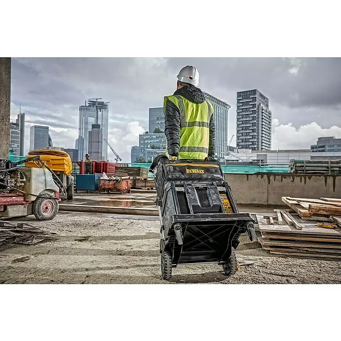 DeWalt T-STAK Bolsa para herramientas - L x An x Al: 25 x 45 x 35 cm, Textil, Capacidad de carga: 30 kg - Un trabajador arrastra un sistema de almacenamiento de herramientas con ruedas DEWALT TSTAK negro y amarillo en una obra.