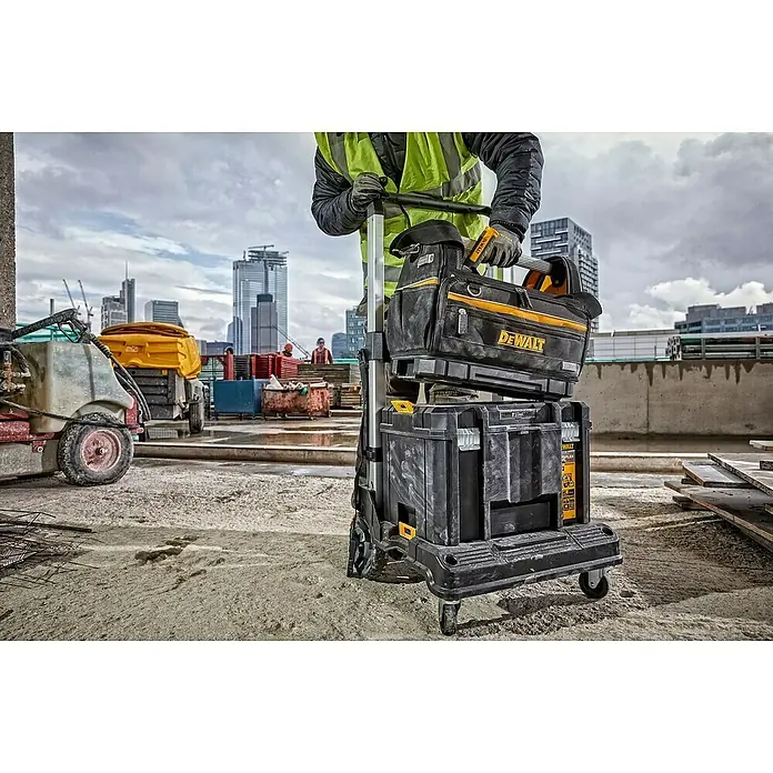 DeWalt T-STAK Bolsa para herramientas - L x An x Al: 25 x 45 x 35 cm, Textil, Capacidad de carga: 30 kg - Bolsa de herramientas DEWALT negra y amarilla y cajas de herramientas apiladas en un carrito, usadas por un trabajador en una obra.