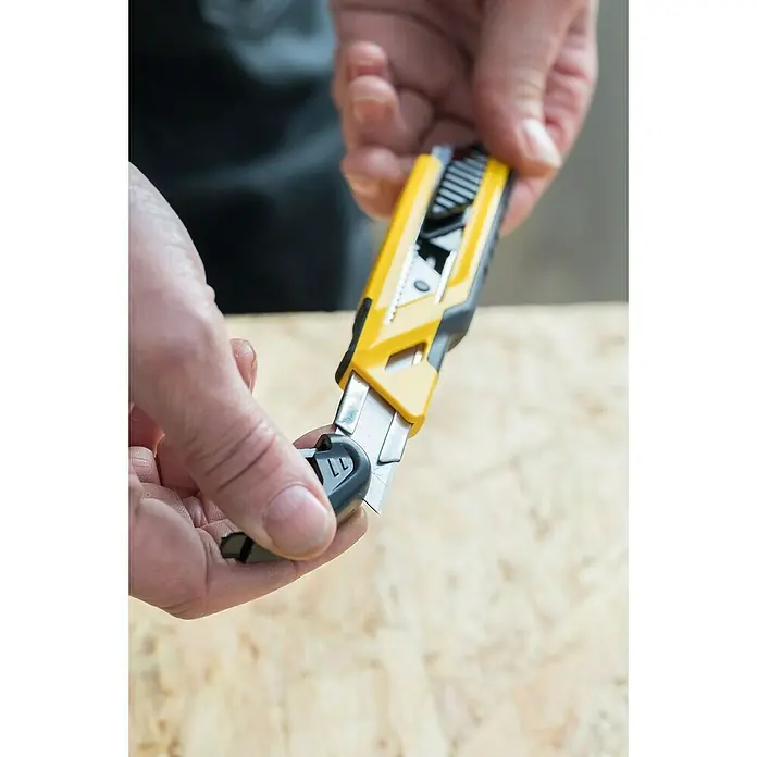 Stanley Cuttermesser Comfort Cut 18mm - Klingenbreite: 18 mm, Abbrechklinge - Detailaufnahme eines gelben Universalmesser, das von einer Person bedient wird, um die Klinge zu wechseln.