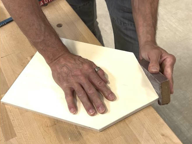 Holzplatte in Form einer Hausseite wird abgeschliffen