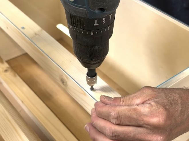 Acrylglas wird auf das Grundgerüst vom DIY Gewächshaus mit Schrauben angebracht