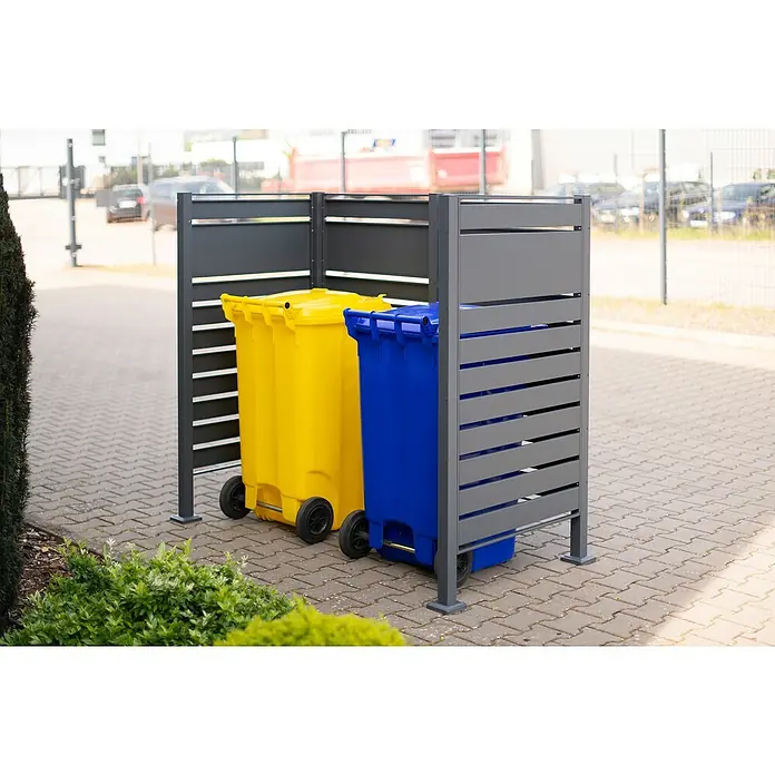 Westmann Mülltonnenbox Verkleidung Planum - 90 x 170 x 150 cm, Anthrazit - Gelbe und blaue Mülltonnen, die in einer modernen, grauen Mülltonnenbox mit horizontalen Lamellen auf Pflastersteinen stehen.