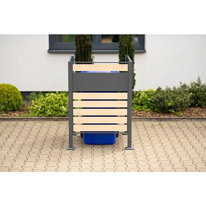 Westmann Mülltonnenbox Verkleidung Planum - 90 x 90 x 120 cm, Anthrazit/Holzoptik - Bild eines Mülltonnenbox mit Holzlamellen und grauem Metallrahmen, die eine blaue Mülltonne auf einem gepflasterten Bereich umgibt.