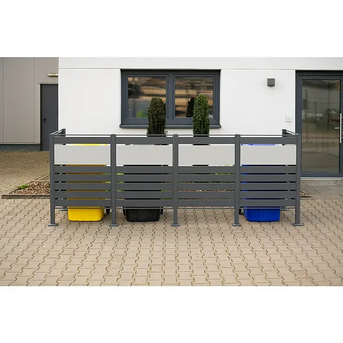 Westmann Mülltonnenbox Verkleidung Planum - 90 x 330 x 120 cm, Anthrazit/Grau - Eine graue Mülltonnenbox mit drei Fächern, die gelbe, schwarze und blaue Mülltonnen verdeckt und mit zwei kleinen Bäumen dekoriert ist.