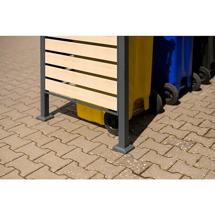 Westmann Mülltonnenbox Verkleidung Planum - 90 x 330 x 120 cm, Anthrazit/Holzoptik - Nahaufnahme einer stilvollen Mülltonnenbox mit Holzverkleidung und grauen Metallelementen auf Pflastersteinen. Praktische und ästhetische Lösung.