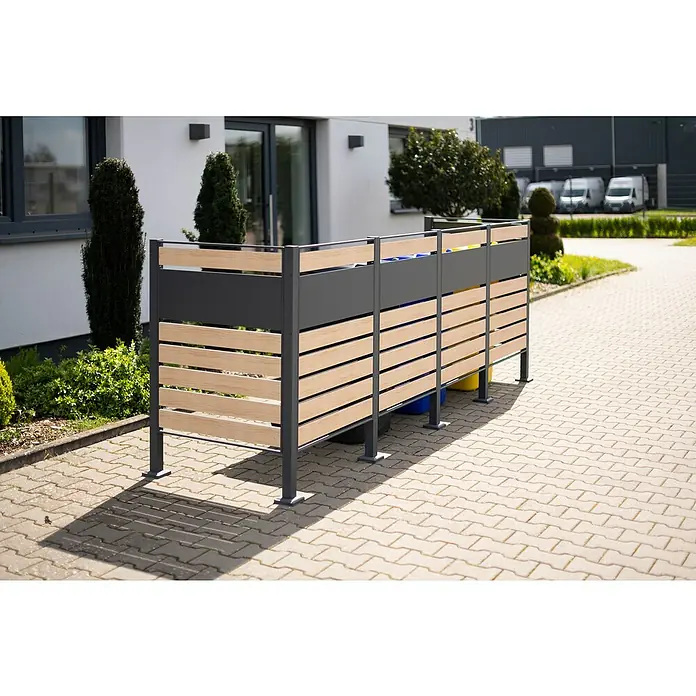 Westmann Mülltonnenbox Verkleidung Planum - 90 x 330 x 120 cm, Anthrazit/Holzoptik - Außenaufnahme einer modernen Mülltonnenbox mit Holzverkleidung vor einem Wohngebäude. Die Box ist schlicht und funktionell gestaltet.