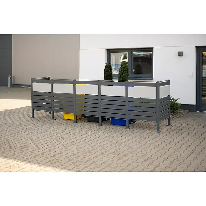 Westmann Mülltonnenbox Verkleidung Planum - 90 x 410 x 120 cm, Anthrazit/Grau - Abfallbehälterbox aus Metall mit Mülltonnen in Gelb, Grau und Blau, die auf einem gepflasterten Bereich platziert sind.