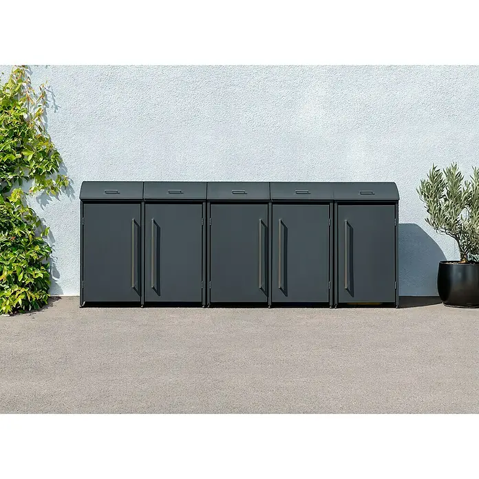 Westmann Mülltonnenbox Moderna - Stahl, Anthrazit, Geeignet für Anzahl Mülltonnen: 5 Stk. - Eine Reihe grauer Mülltonnenboxen aus Metall stehen vor einer weißen Wand, flankiert von Grünpflanzen. Die Boxen haben schlichte, moderne Griffe.