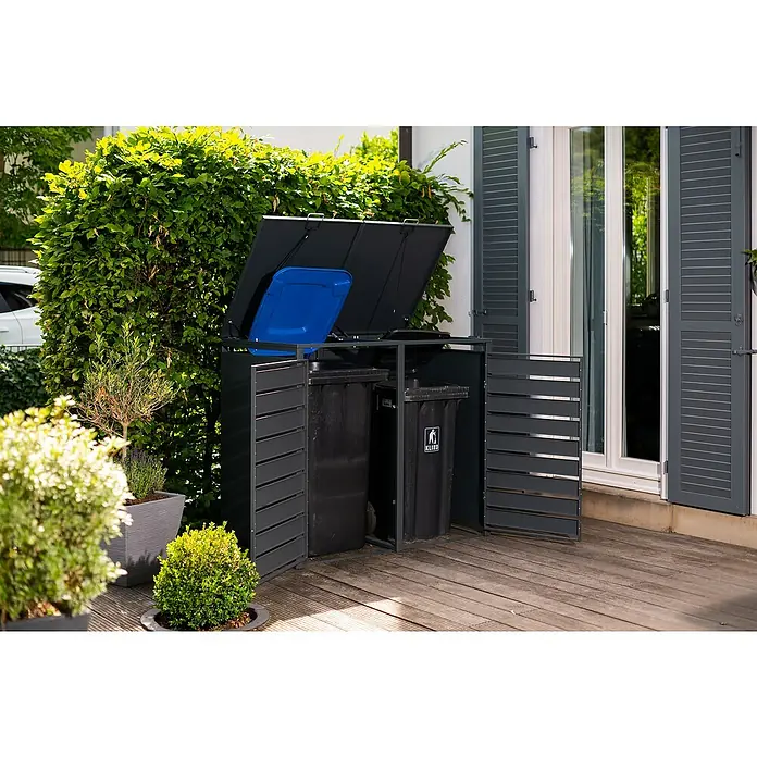 Westmann Mülltonnenbox Lacina - Stahl, Anthrazit/Braun, Geeignet für Anzahl Mülltonnen: 2 Stk. - Abfalltonnenbox aus dunklem Metall mit zwei Mülltonnen und einer blauen Box darin, vor einer grünen Hecke auf einer Terrasse.