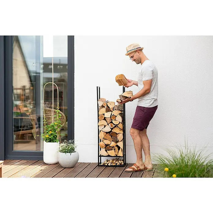 Westmann Kaminholzregal Porthos - 40 x 20 x 120 cm, Stahl, Schwarz - Ein Mann befüllt einen modernen Kaminholzständer mit Holz. Praktische und stilvolle Kaminholzaufbewahrung für den Innen- und Außenbereich.