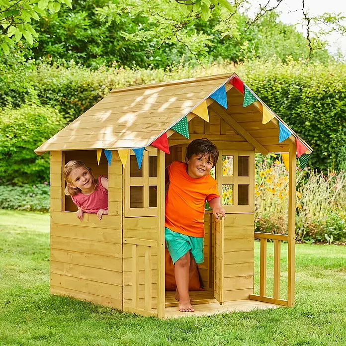 Zwerkules Spielhaus Villa - L x B x H: 137 x 121 x 140 cm, Holz, Natur - Ein hölzernes Spielhaus für Kinder mit bunten Wimpeln, in dem ein Junge und ein Mädchen spielen. Das Haus steht im Garten.