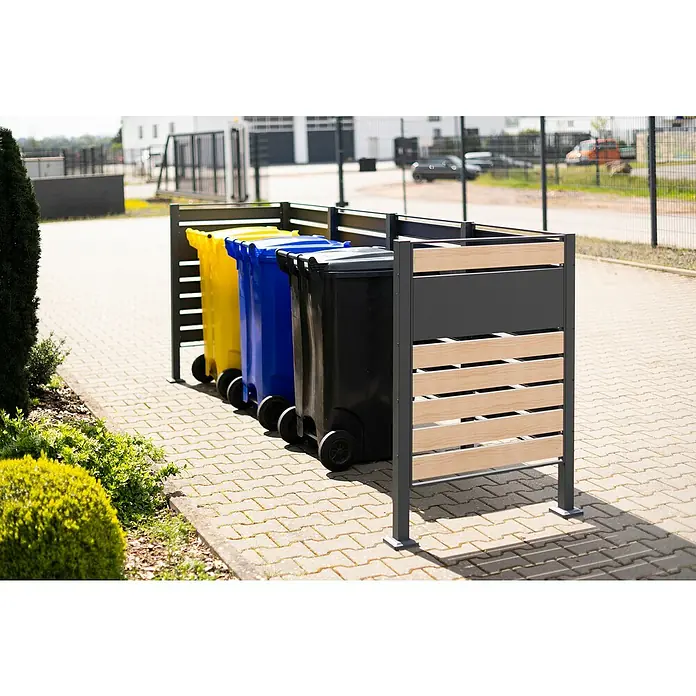Westmann Mülltonnenbox Verkleidung Planum - 90 x 330 x 120 cm, Anthrazit/Holzoptik - Mülltonnenbox mit drei bunten Mülltonnen (gelb, blau, schwarz) vor einem modernen Gebäude. Praktische und stilvolle Lösung für die Müllentsorgung.