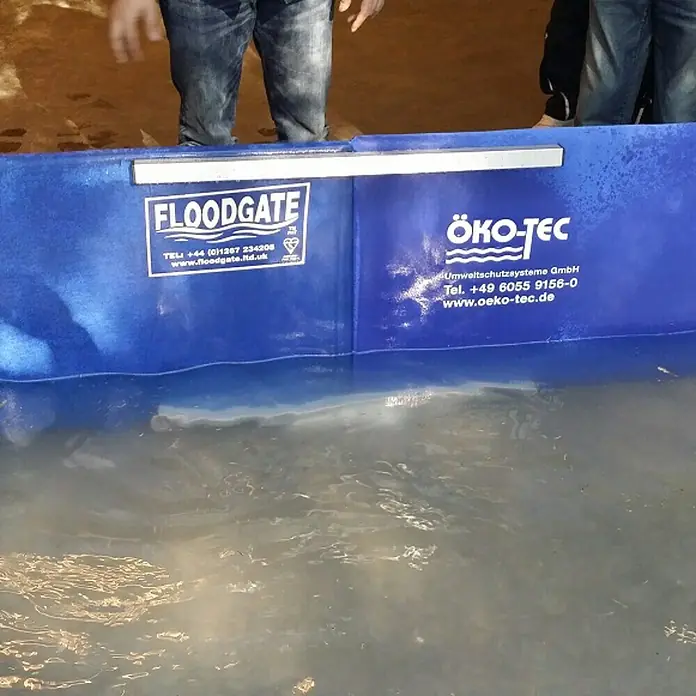 Öko-Tec SteckverbinderRegular/Medium, Montageart: Stecken - Eine blaue FLOODGATE- und ÖKO-TEC-Hochwassersperre, die im Wasser steht und Schutz vor Überschwemmungen bietet.