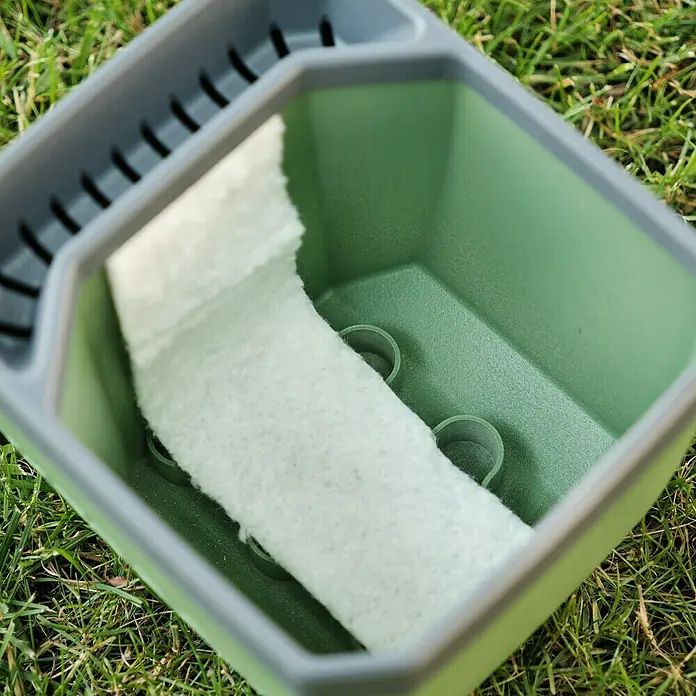 Gusta Garden Kräutertopf Herbs Buddy - 16 x 14,3 x 13,6 cm, Kunststoff, Blau, 1 Stk. - Nahaufnahme eines grünen Spülbecken-Organizers mit einem weißen Schwamm darin, der auf einer grünen Rasenfläche steht.